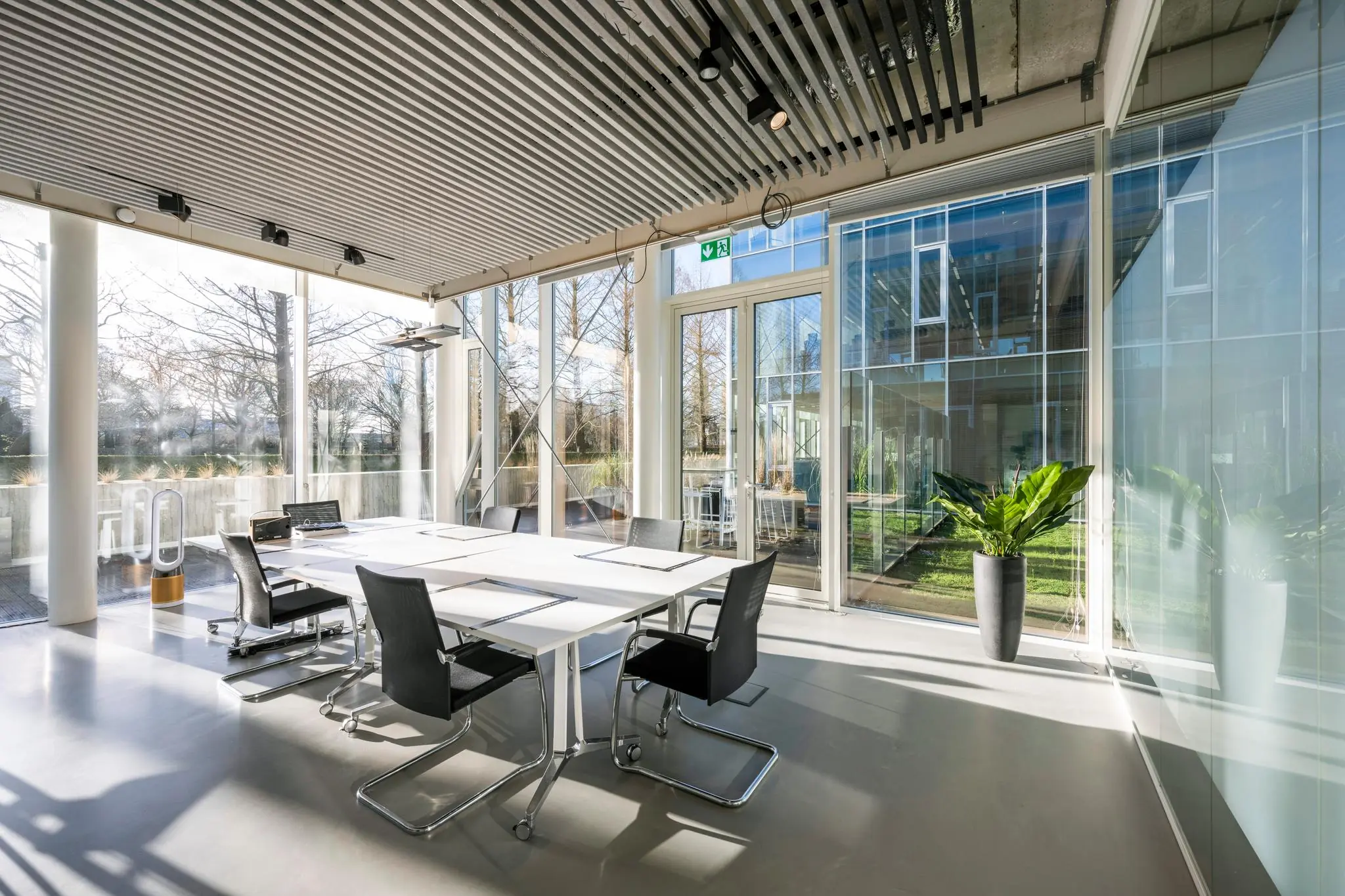 Lichte en moderne vergaderruimte aan de Fred. Roeskestraat met glazen wanden en uitzicht op een binnentuin.